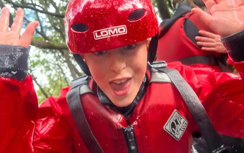 Child in ghyll scrambling kit pulling a face at the camera