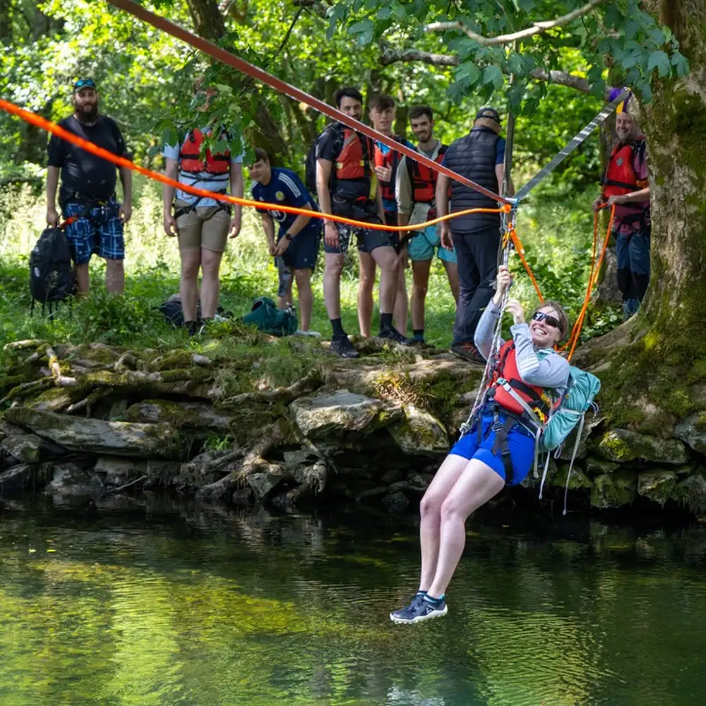 Woman on a zip wire crossing a river in the Lake District