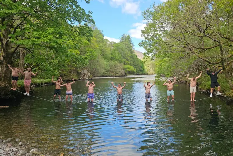 Group of men crossing a river on a rope bridge