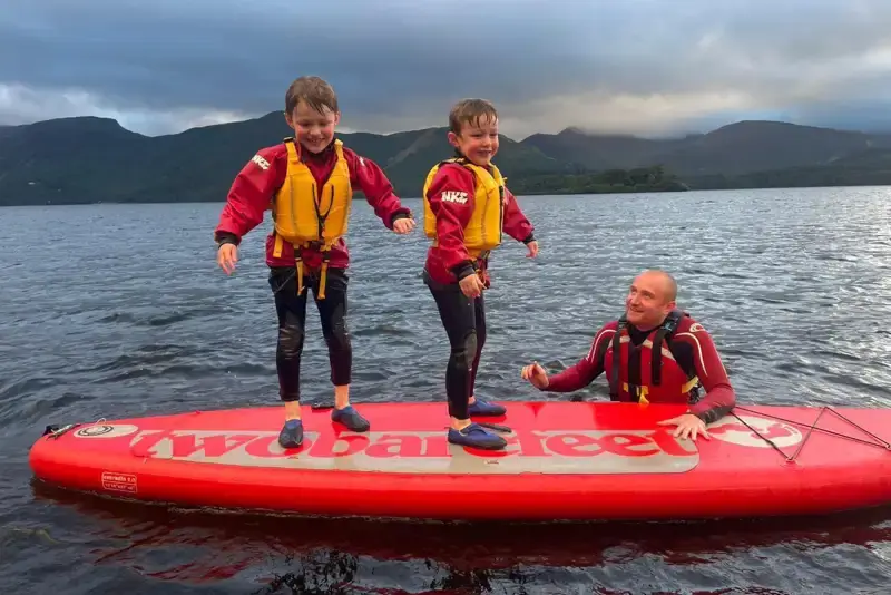 Two young boys on a paddleboard with their dad