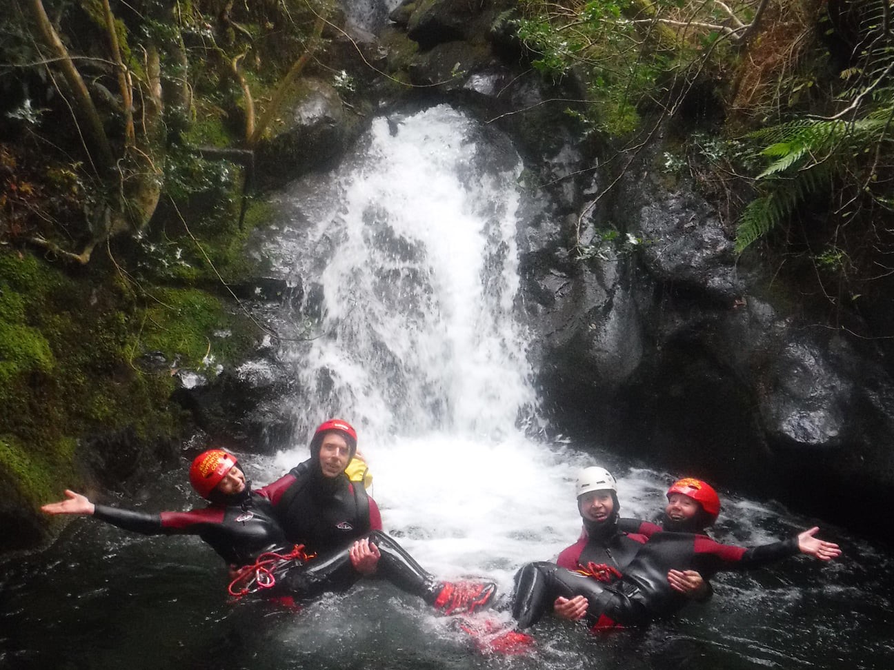 A group canyoning in a waterfall in the rain