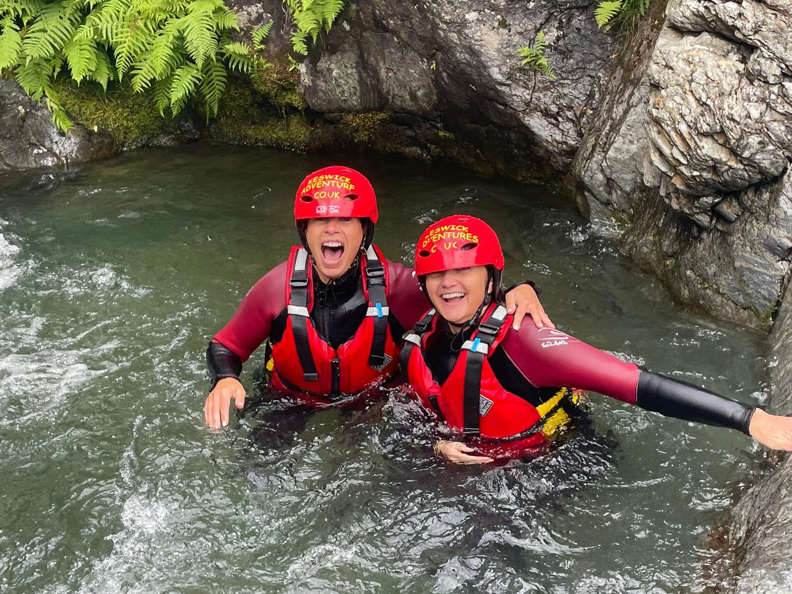 Two female friends laughing while ghyll scrambling in the Lake District