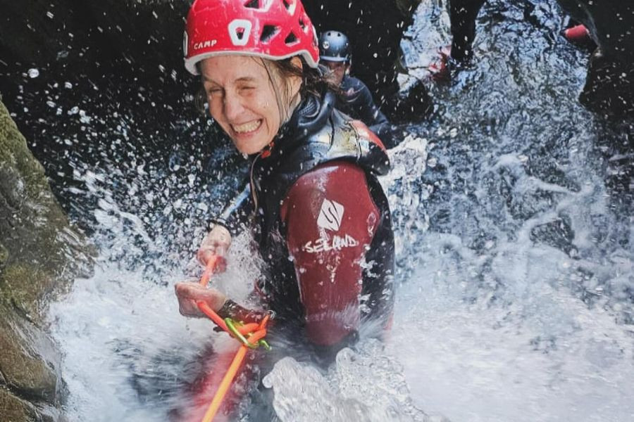 Woman being splashed by a waterfall in a ghyll